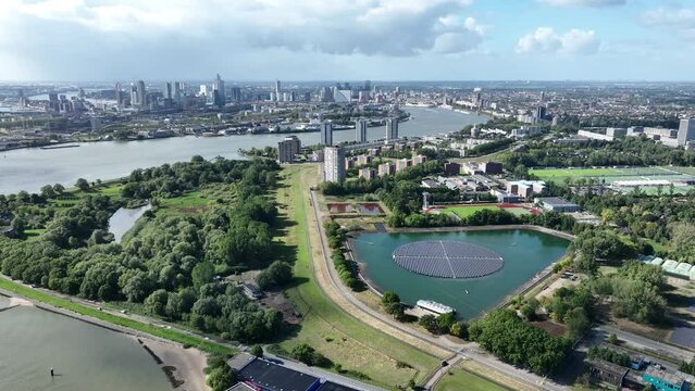 Rotterdam city skyline in the distance and the Feijenoord district. Nieuwe Maas river and sustainable solar panels on inland water.