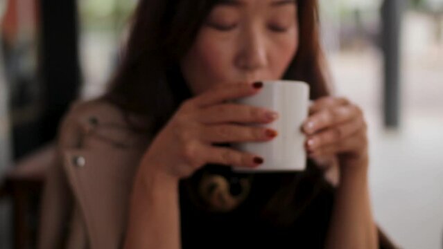 Asian woman drinking coffee at the cafe outside.