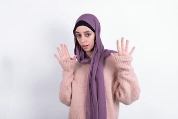 beautiful muslim woman wearing hijab and warm jumper over white background Moving away hands palms...
