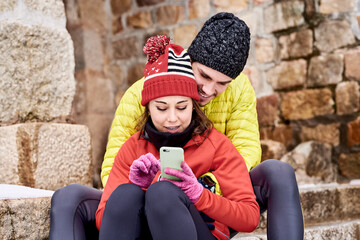 Couple using smartphone together in winter