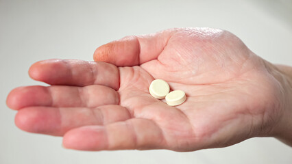 Wrinkled palms of mature woman with painkiller headache pills on blurred background. Female person shows effective medication to fight pain closeup
