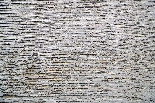 Gray decorative plaster on the wall with pressed horizontal stripes. Plaster background
