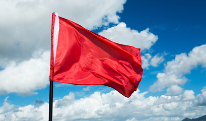 Red flag waving against blue sky