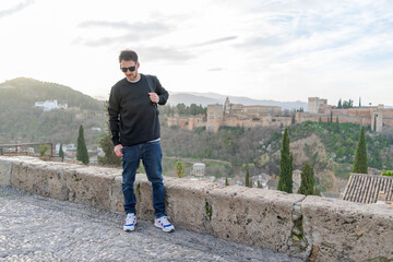 A Caucasian man walking along the San Nicolas viewpoint in Granada.