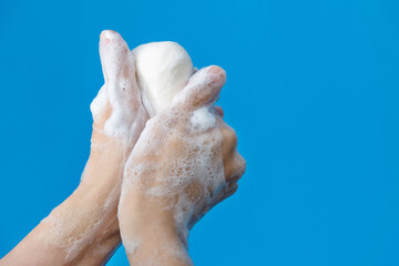 Woman washing hands with soap on blue background