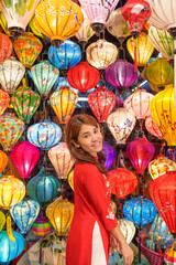 Fototapeta na wymiar happy woman wearing Ao Dai Vietnamese dress with colorful lanterns, traveler sightseeing at Hoi An ancient town in central Vietnam.landmark for tourist attractions.Vietnam and Southeast travel concept