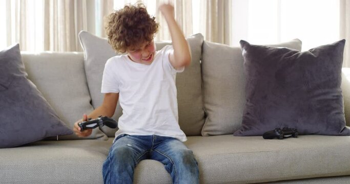 Gaming, winner and child on video game console in home living room excited for achievement or online esport competition. Winning, yes and gamer kid with playstation games for holiday on sofa or couch