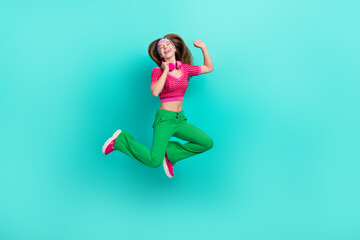 Fototapeta na wymiar Full length photo of charming dreamy schoolgirl wear pink crop top jumping high listening songs isolated turquoise color background