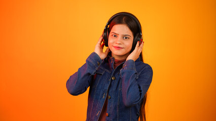 Young woman listening music with wireless headphones on her head, happy teenage girl enjoying music isolated over colour background