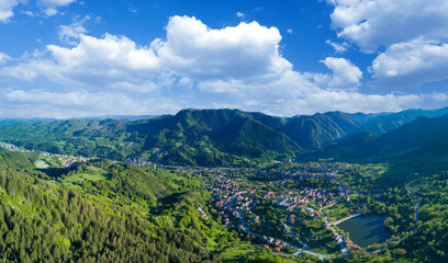Fototapeta na wymiar Bulgarian town Smolyan with lake, vegetation and clouds. Rhodope Mountains. Panorama, top view