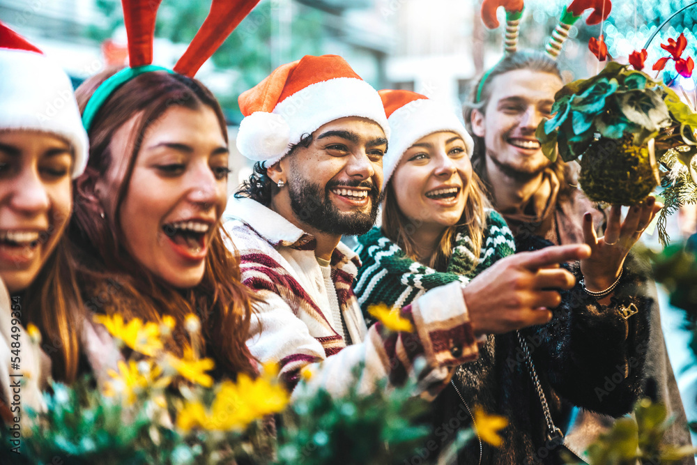 Wall mural happy group of friends having fun at christmas market souvenir shop - cheerful young tourists enjoyi