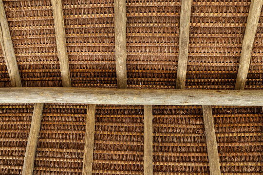 Structure of a roof with piassava, seen from the bottom up, showing its wooden structure and the braiding of straw.
