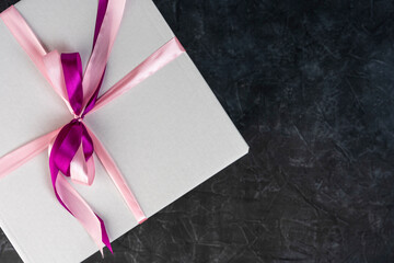 white cardboard gift box tied with a red ribbon on a dark background