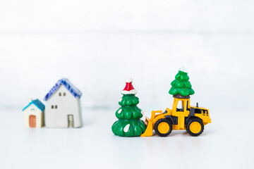 Christmas concept background, Yellow truck delivery Christmas tree over blurred house and tree...