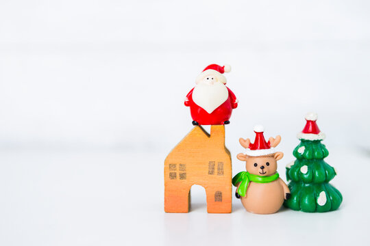 Cute little Santa clause and little reindeer with christmas tree and wooden house model on white bacground, Christmas concept background, festive season background