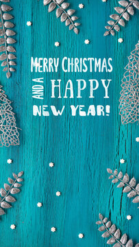 Silver minimal Christmas background with sugar stars and exotic fern leaves on turquoise cracked wood. Caption, Xmas greeting Merry Christmas and a Happy New Year on blackboard, chalk board.