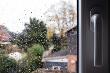 Window with raindrops on the glass outside, against the backdrop of the yard. Place for text. 