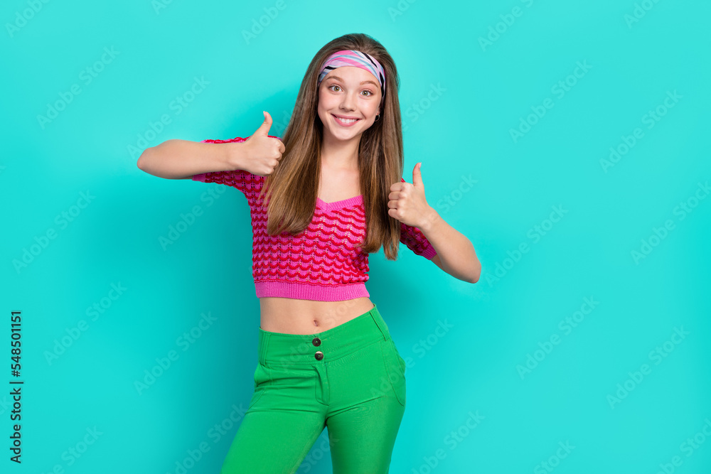 Wall mural Portrait of positive optimistic girl with long hairstyle dressed pink top headband showing thumbs up isolated on teal color background