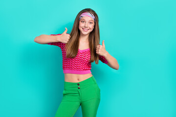 Portrait of positive optimistic girl with long hairstyle dressed pink top headband showing thumbs up isolated on teal color background