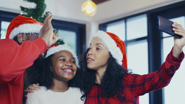 A joyful African American family celebrates Christmas Day at home with a Christmas tree in winter day, gift-giving, celebration, reunion family in the festive season.