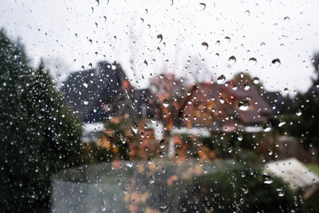 Raindrops on the window glass outside, against the background of the yard. Copy space. 