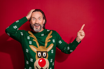 Photo of mature age pensioner man wear green sweater touch hand head excited surprised finger direct copyspace gift isolated on red color background