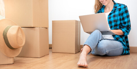 Fototapeta na wymiar Unrecognizable portrait young happy woman sitting on the floor with many boxes, working with computer in a new house. - Caucasian beautiful girl - High quality photo