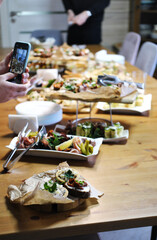 Festive family dinner. Female hands take a photo of food on a mobile phone
