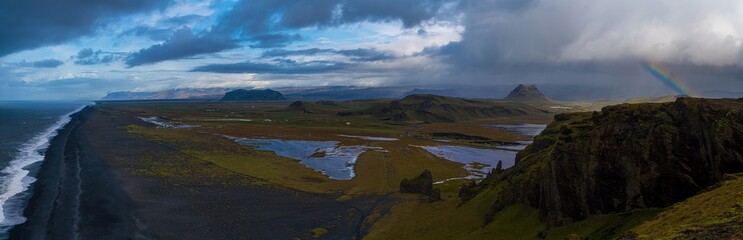 panoramic mountain view of valley and arctic sea under a rainbow rainstorm 