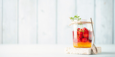 Honey fermentation of fruits and berries. Glass jars with fermented honey cranberry and thyme on a blue background. Homemade remedy for immunity