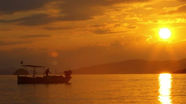 At sunset, the fisherman pulls the chain of his boat out of the sea. silhouette image.