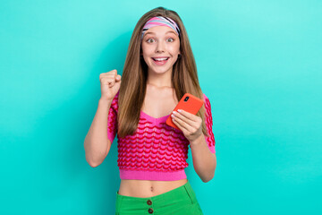 Portrait of impressed lucky successful girl with long hairstyle dressed pink top hold phone win lottery isolated on teal color background