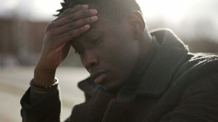 Fototapeta premium Worried black man suffering alone in emotional pain outside in city sidewalk street2