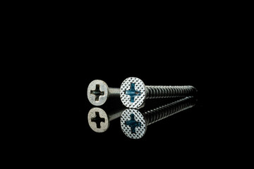 Isolated image of metal iron screw with phillip head with black background.