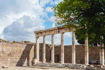 Obraz premium Colonnade of the ruined Temple of Trajan in Pergamon Ancient City. Corinthian order, II century AD. Beautiful clouds at background. History, art or architecture concept. Bergama, Turkey