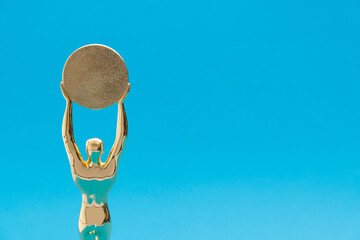 Golden statuette of a man on blue background