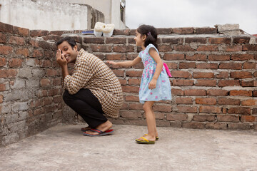 Father playing hide and seek with his daughter in the backyard
