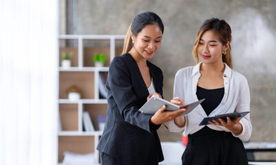 Obraz premium The collaborative process of young Asian business people team standing working together discussing, researching, brainstorming, and planning work in the office