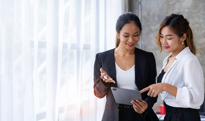 The collaborative process of young Asian business people team standing working with tablets...