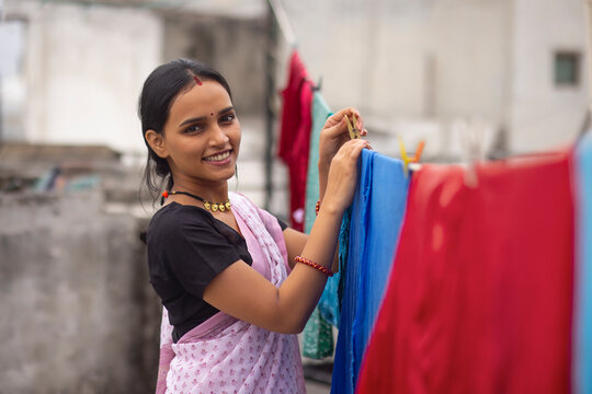 Woman hanging out wet clothes on washing line in the backyard