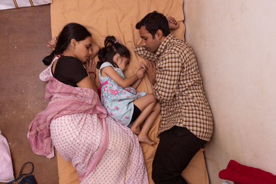 Overhead view of young couple and their daughter sleeping together on the bed