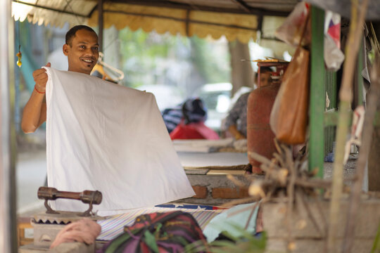 Indian Man, Dhobi, ironing clothes outside a colony for its residents  