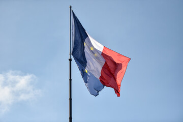 France and European Union flags on a pole are blown by the wind. Blue sky on background