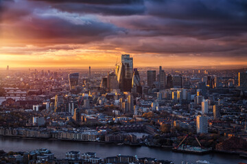 The skyline of the City of London with the modern office skyscrapers reflecting the warm sunlight of a cloudy winter sunset, England