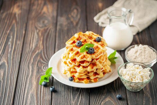 Homemade cottage cheese waffles with ingredients on wooden background