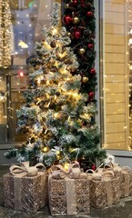 Christmas tree with cones, snow, a golden garland of lights and gifts - 548510983