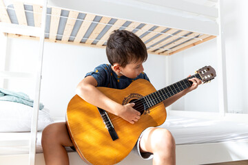 Boy learning to play acoustic guitar. Boy is practicing acoustic guitar in his room