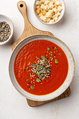 Creamy warm tomato soup served with sesam seeds and micro greens, overhead shot