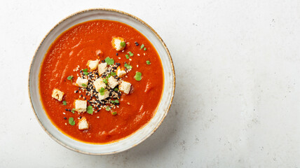Round bowl with garnished pureed tomato soup, light background, copy space 