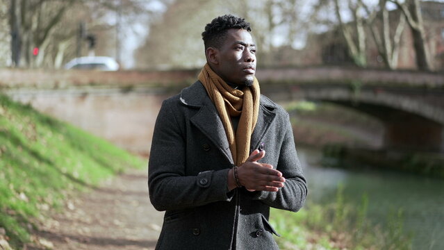 Young black man walking outside in nature during winter season